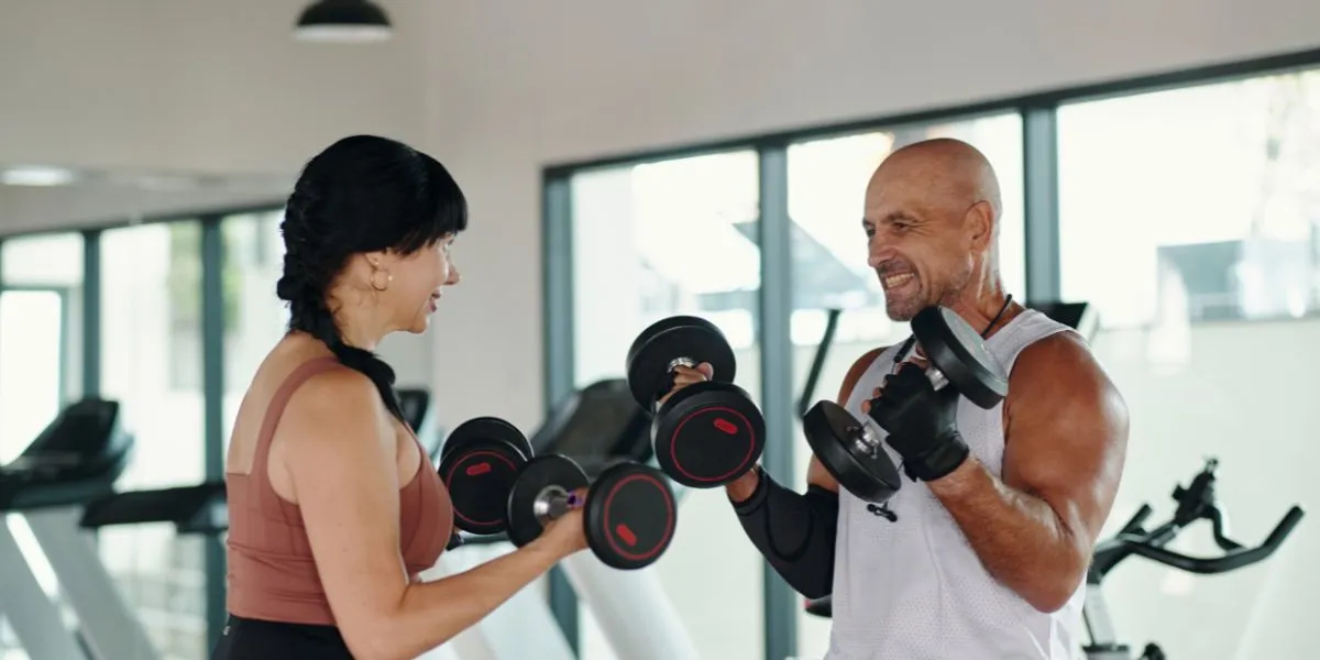 Personal trainer coaching a woman through dumbbell curls in a bright gym