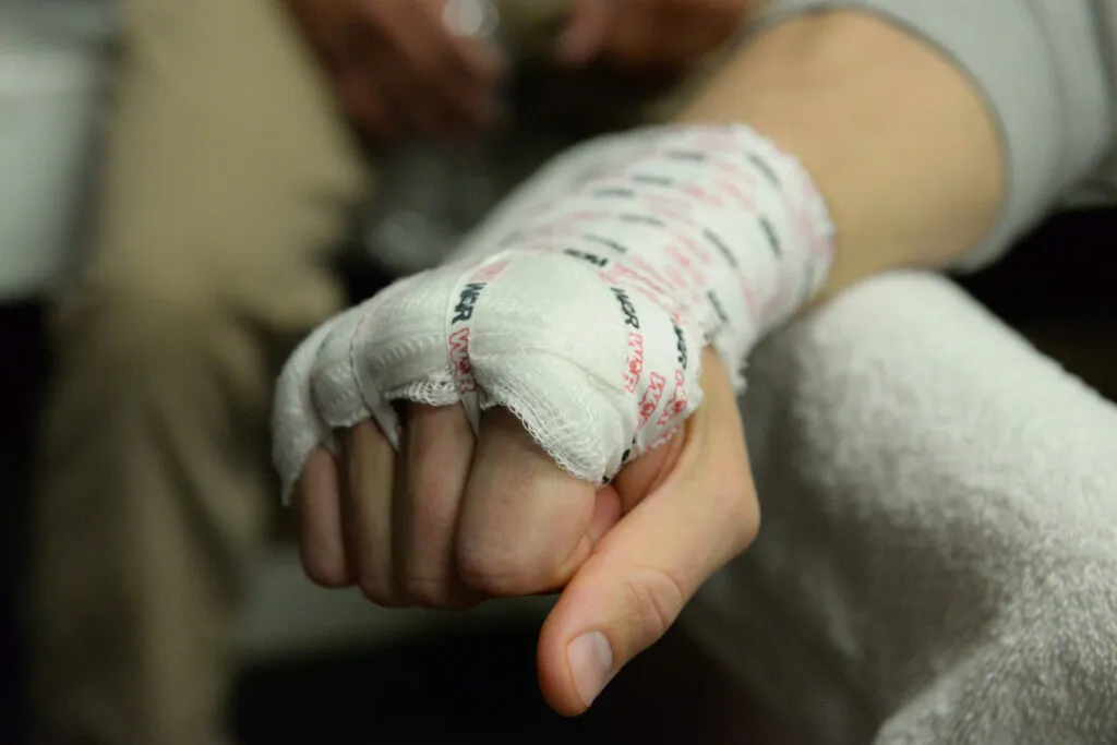 Side view of a fist wrapped in white hand wraps, resting on a knee