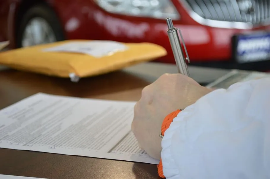 Person signing a document beside a padded envelope