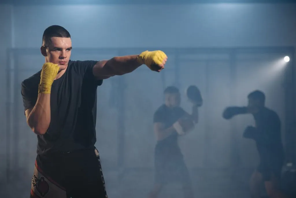 Boxer in yellow hand wraps shadowboxing in a smoky gym