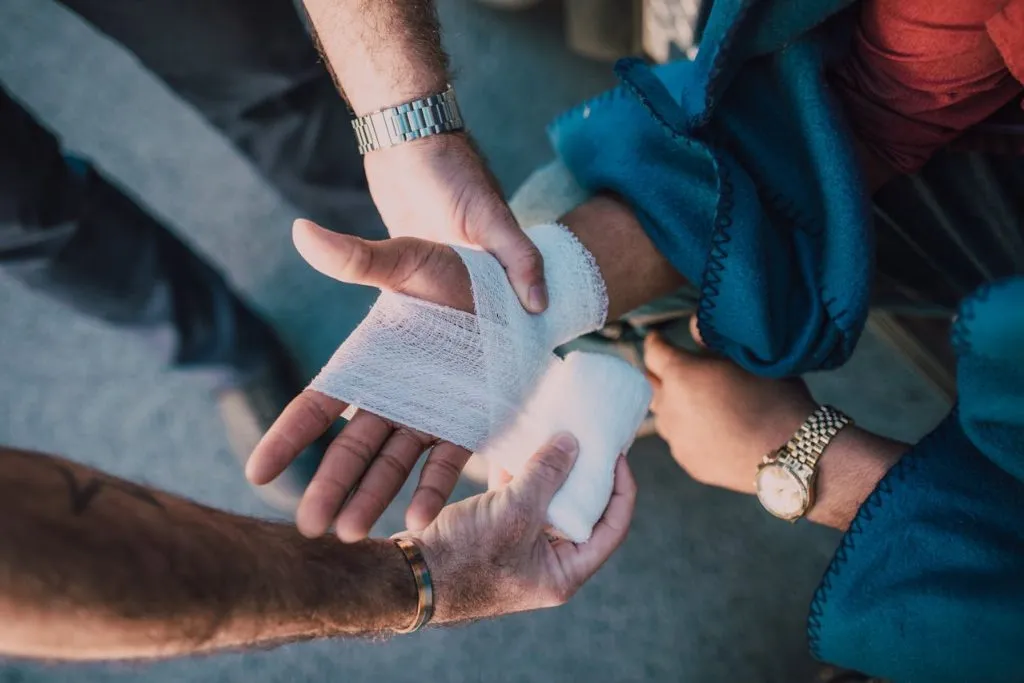 Hands wrapping a bandage around an injured hand