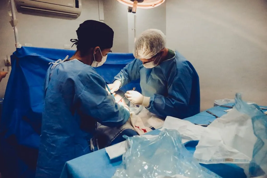 Surgeons in blue scrubs operating in a theatre