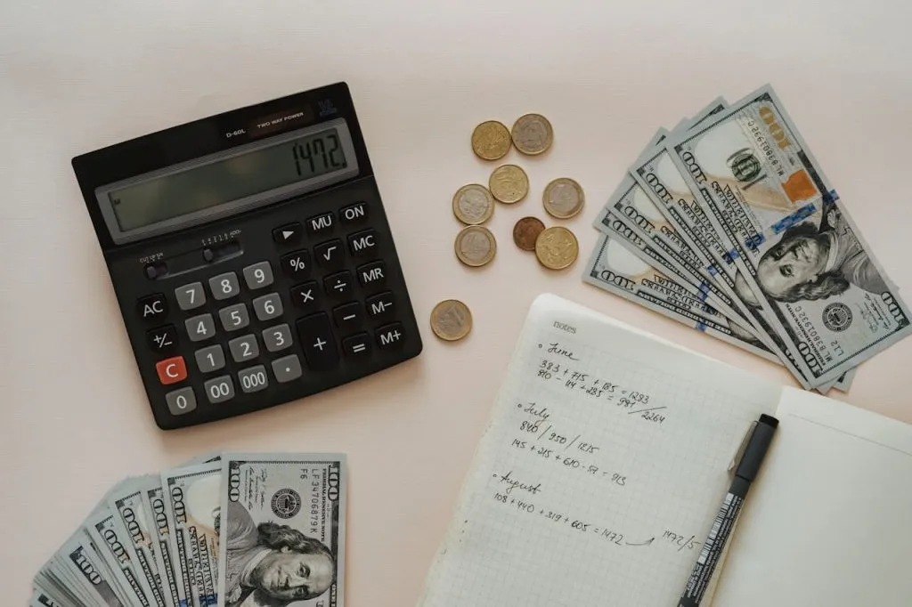 Calculator, coins, banknotes and a handwritten budget on a desk