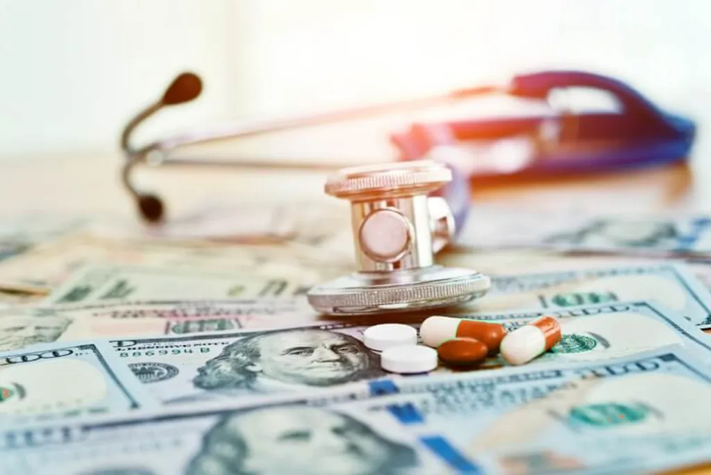 Stethoscope, pills and banknotes spread across a table