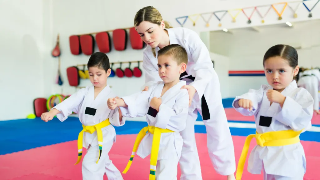 Instructor correcting the stance of young children in white gis and yellow belts