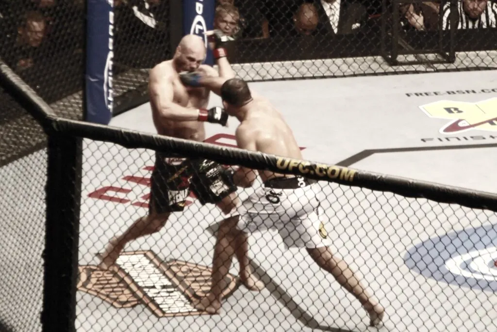 Two MMA fighters clinching in the centre of the cage during a bout