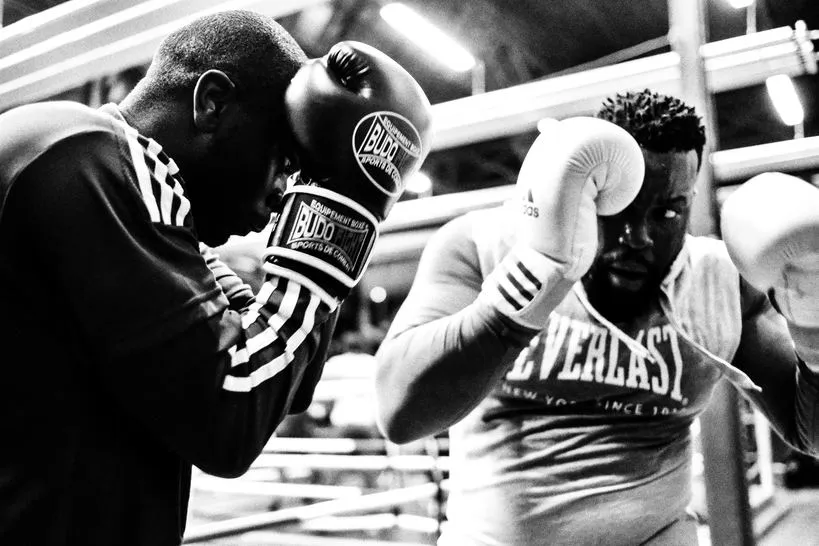 Black and white photo of two boxers in gloves training together