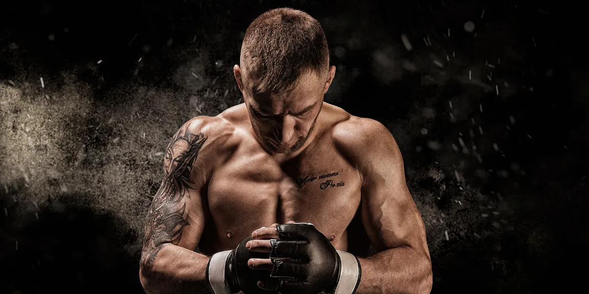 Shirtless fighter in MMA gloves with his head bowed and fists together