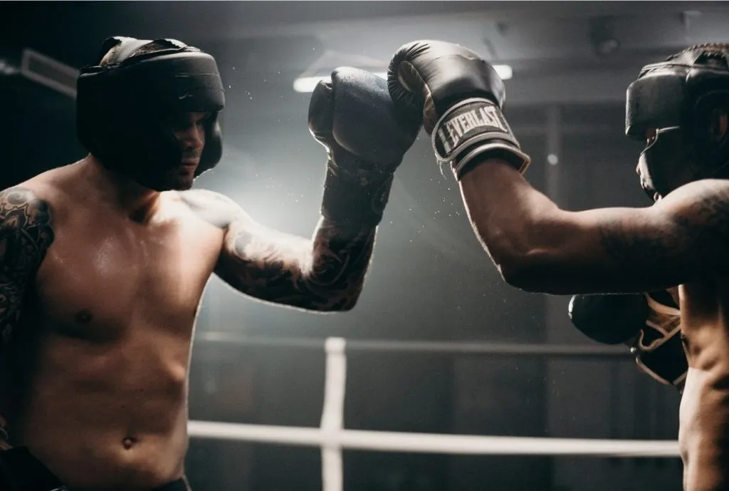 Two boxers in headgear touching gloves before sparring
