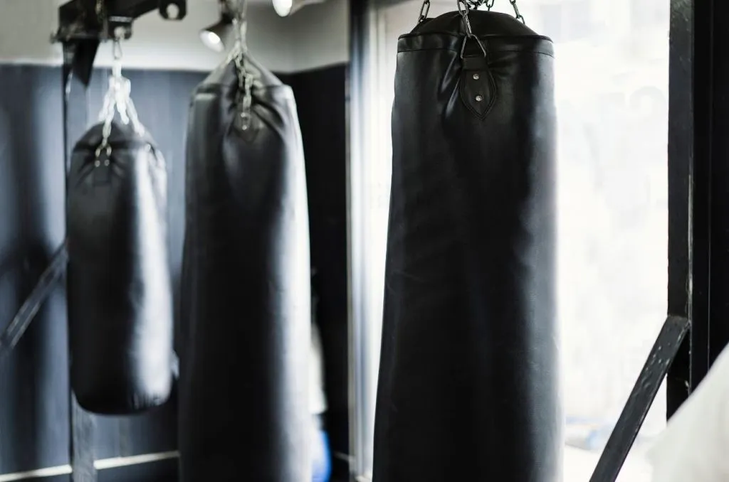 Row of black heavy bags hanging in an empty boxing gym