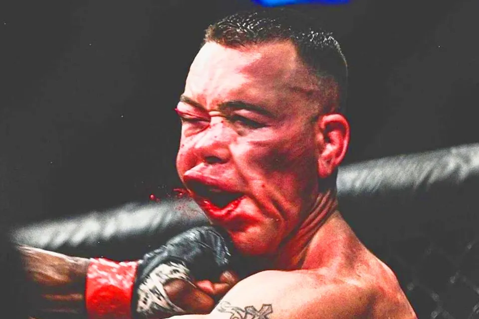 Fighter taking a heavy punch to the jaw in the cage, face distorted by the impact