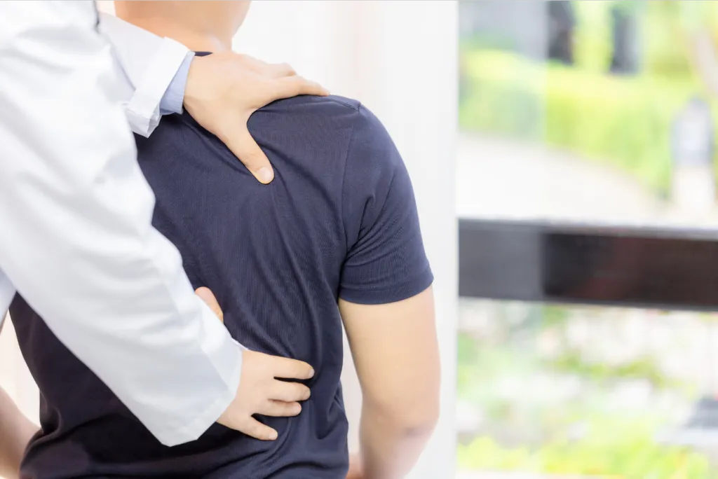 Therapist massaging a man's shoulder during a recovery session