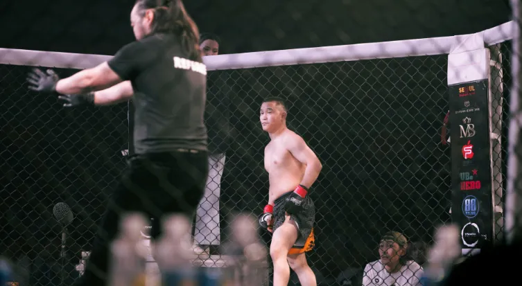 MMA fighter standing in the cage after a bout with the referee nearby