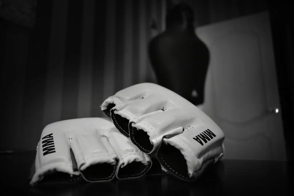 Pair of white MMA gloves resting on a table in a dark gym
