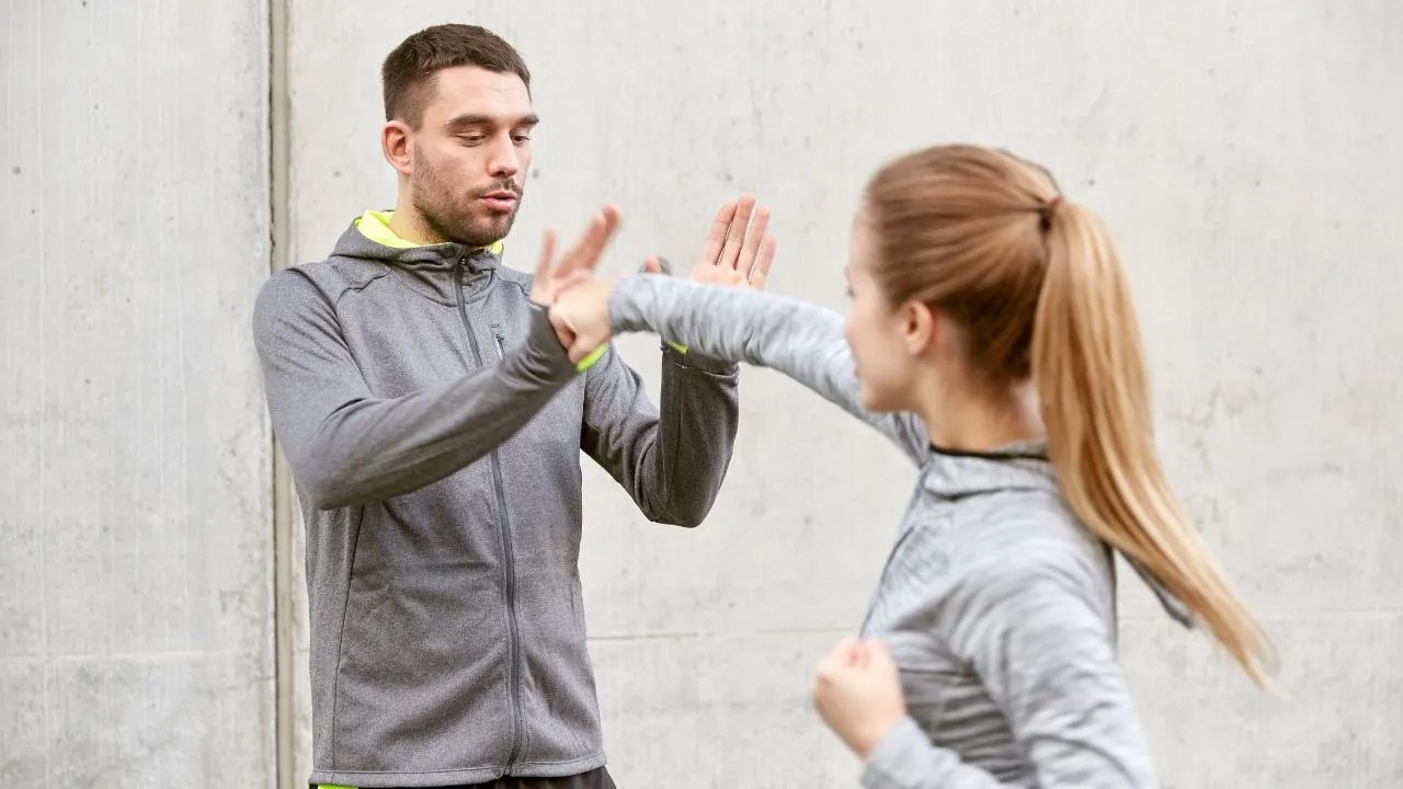 Self-defence instructor teaching a woman to block a strike