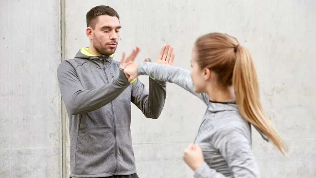 Self-defence instructor teaching a woman to block a strike