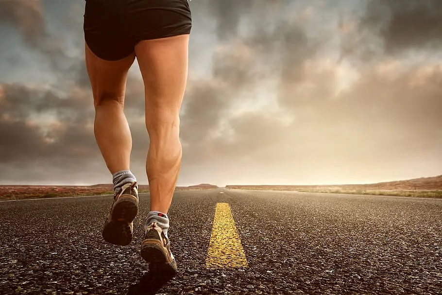 Runner's legs on an open road under a dramatic sky