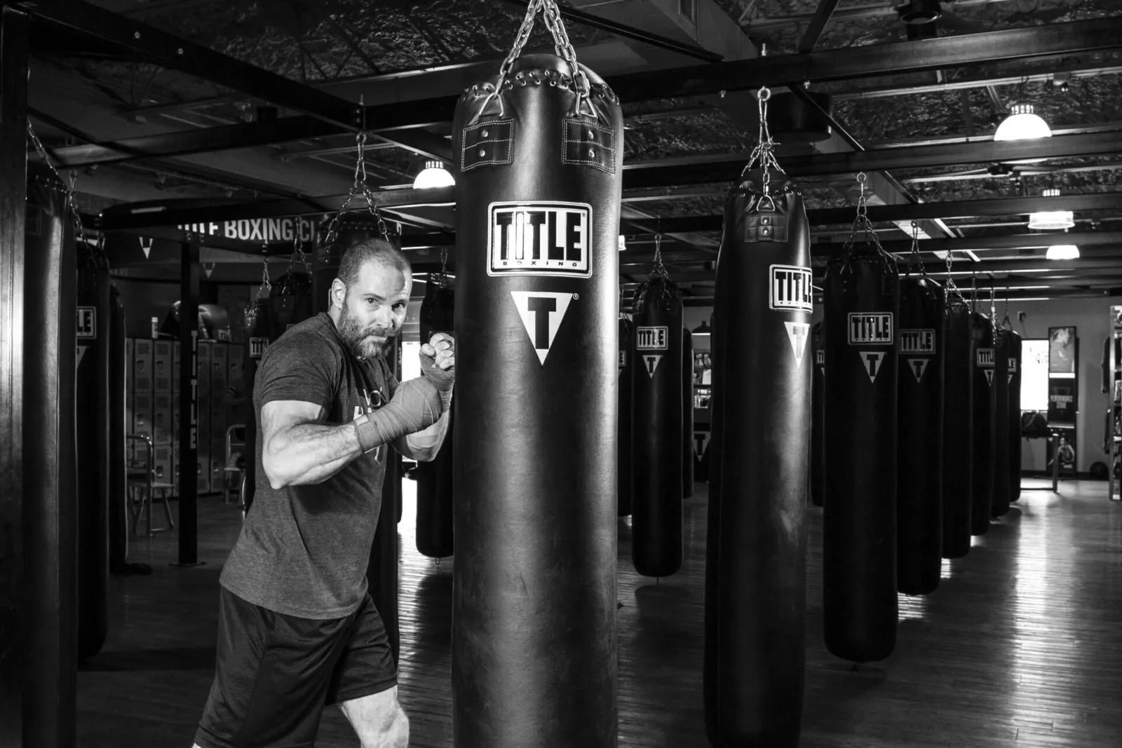 Black and white photo of a boxer working a heavy bag in a gym lined with bags