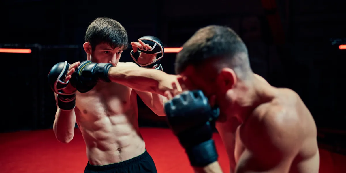 Two MMA fighters sparring in gloves under red light