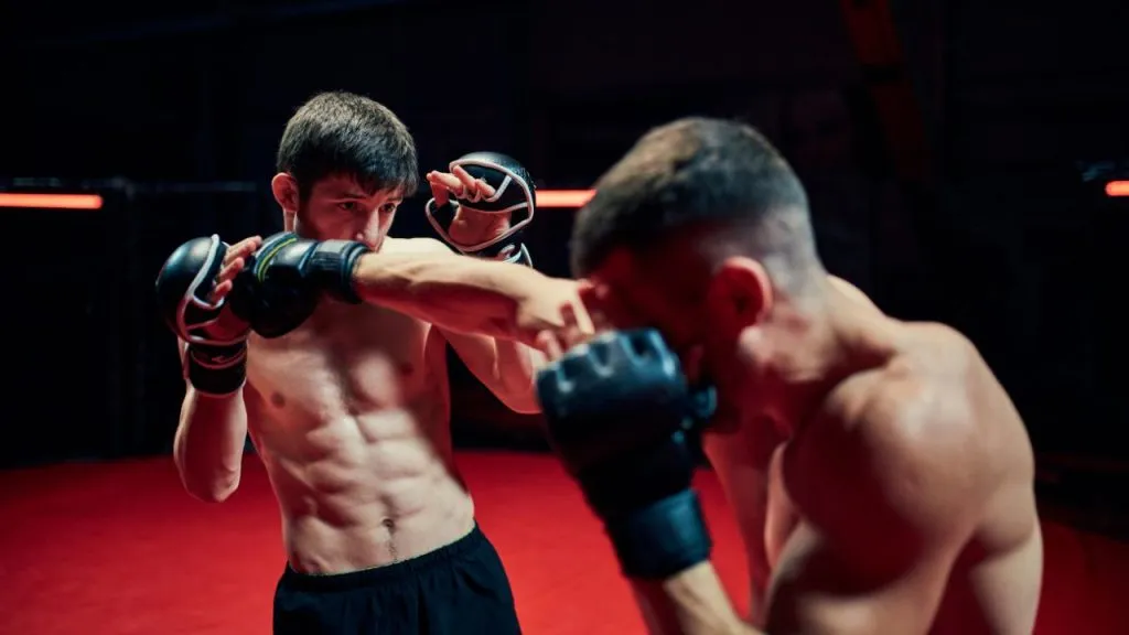 Two MMA fighters sparring in gloves under red light