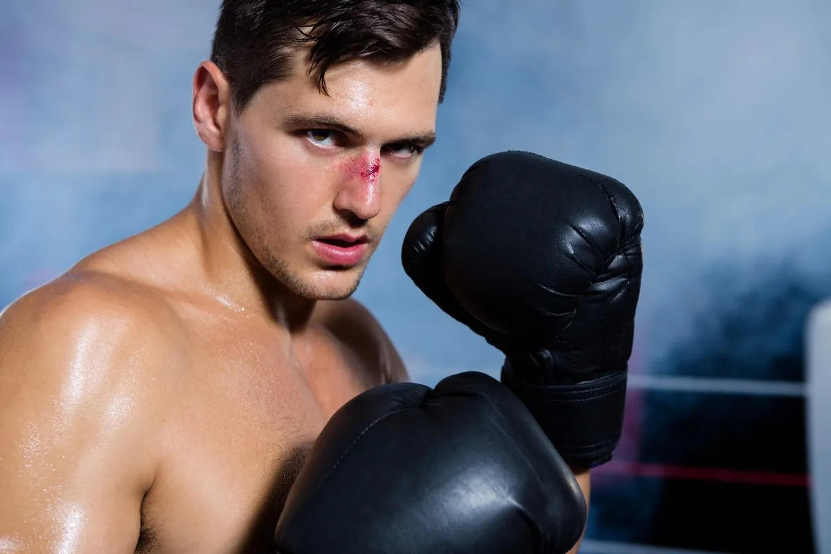 Boxer in black gloves with a bloodied nose, guard raised