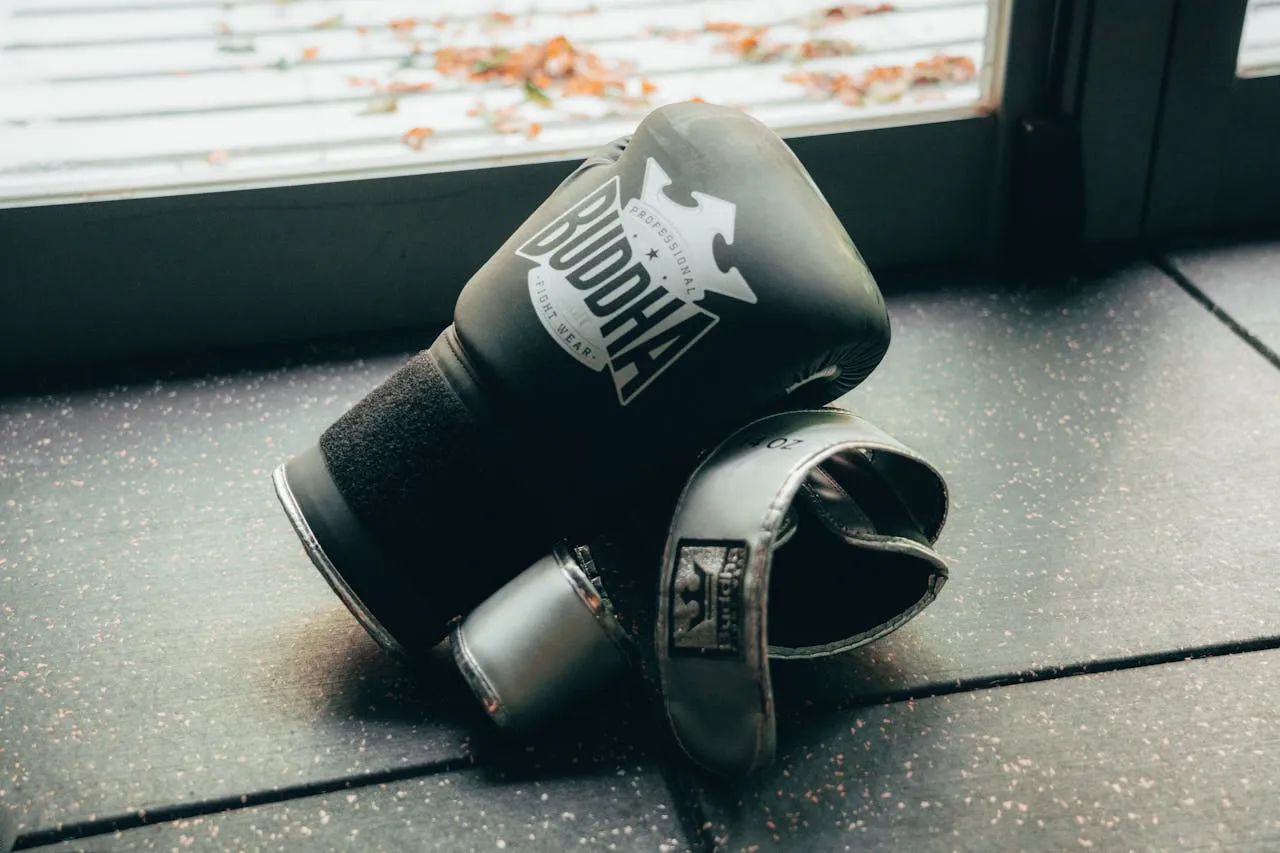 Pair of black boxing gloves resting on the floor by a window