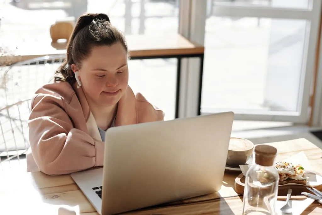 Young woman with Down syndrome working on a laptop at a table