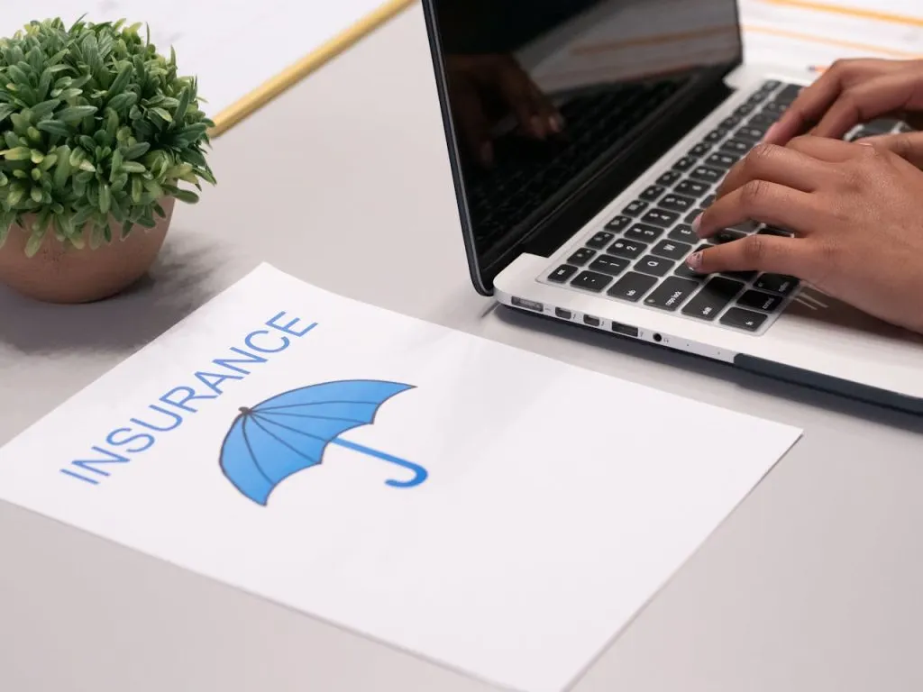 Insurance document with a blue umbrella logo beside a person typing on a laptop