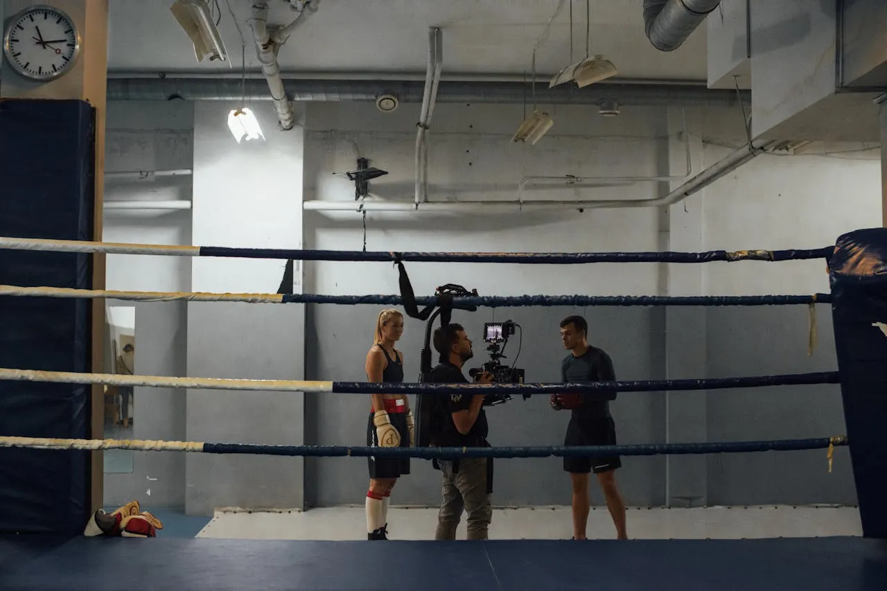 Camera crew filming a female boxer in a ring inside a gym