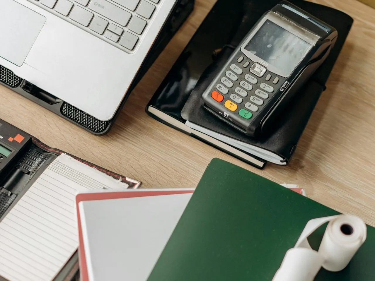 Card payment terminal, laptop and paperwork on a desk