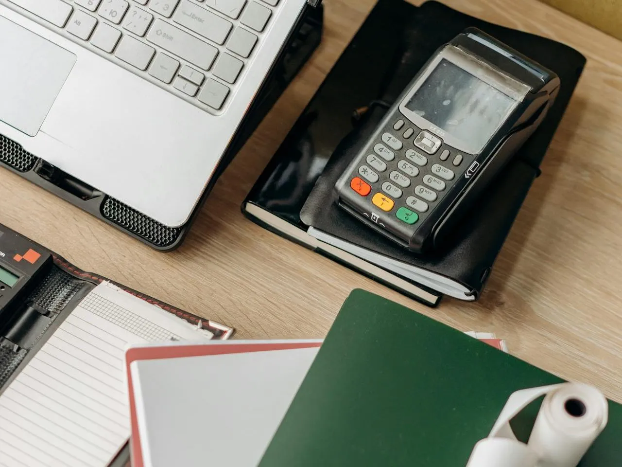Card payment terminal, laptop and paperwork on a desk