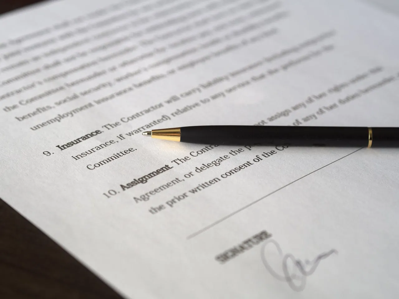 Close-up of an insurance contract clause with a pen resting beside the signature line