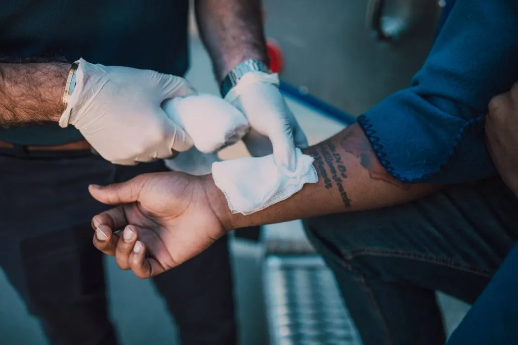 Medic in gloves wrapping a bandage around a fighter's forearm