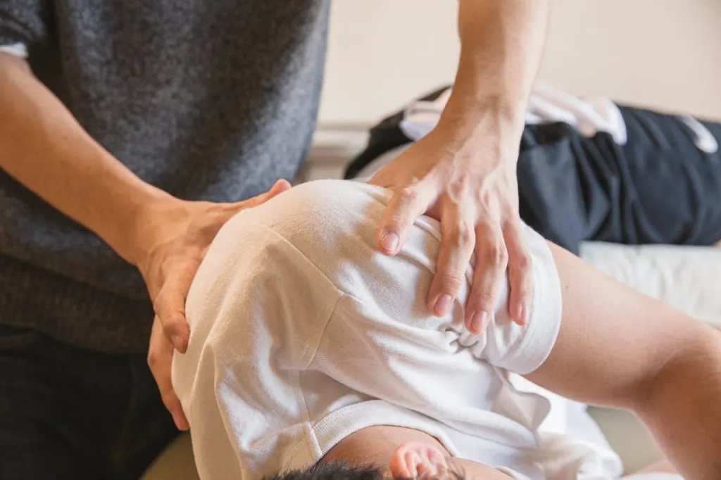 Physiotherapist applying pressure to a patient's shoulder during treatment