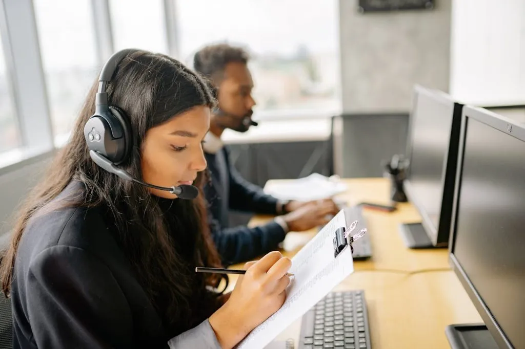 Customer service agent in a headset taking notes at her desk