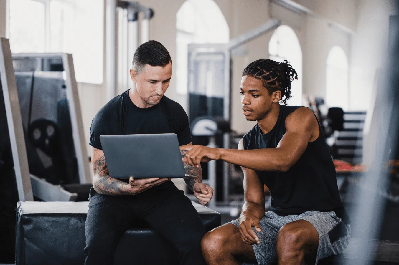Trainer and athlete reviewing something together on a laptop in a gym