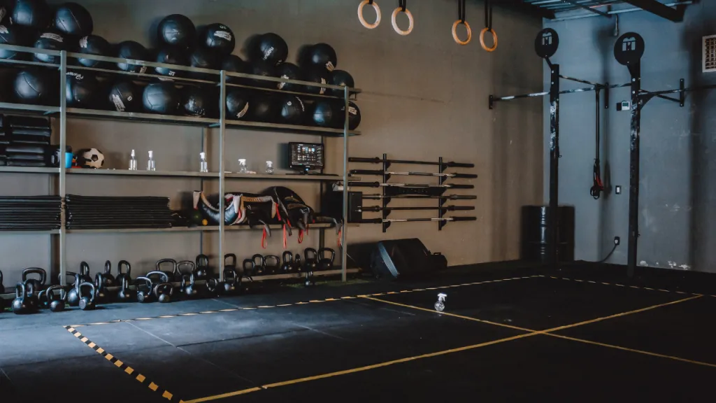 Empty gym with kettlebells, medicine balls and wall-mounted bars and no people