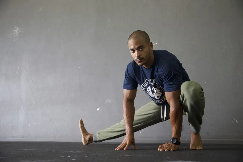 Man stretching in a deep side lunge on a gym floor