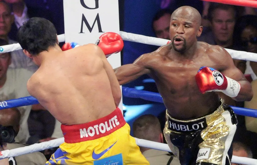 Two professional boxers exchanging punches in the ring at a title fight