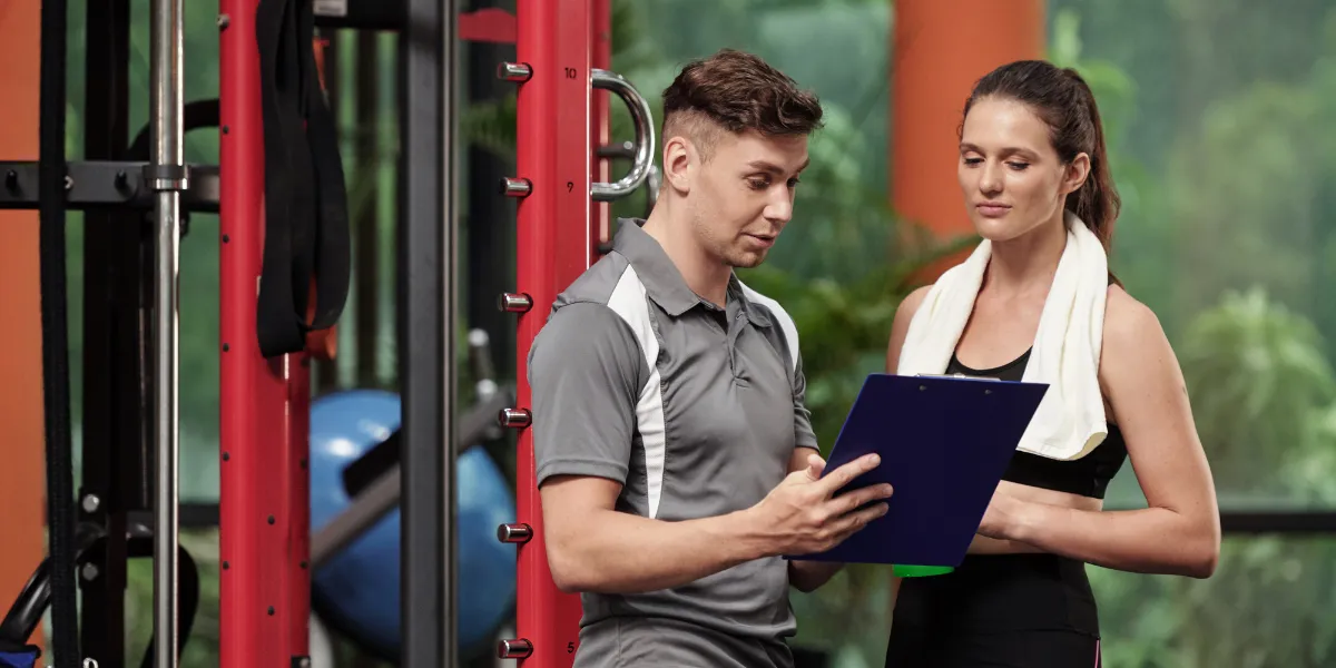 Personal trainer going through a clipboard with a client in a gym