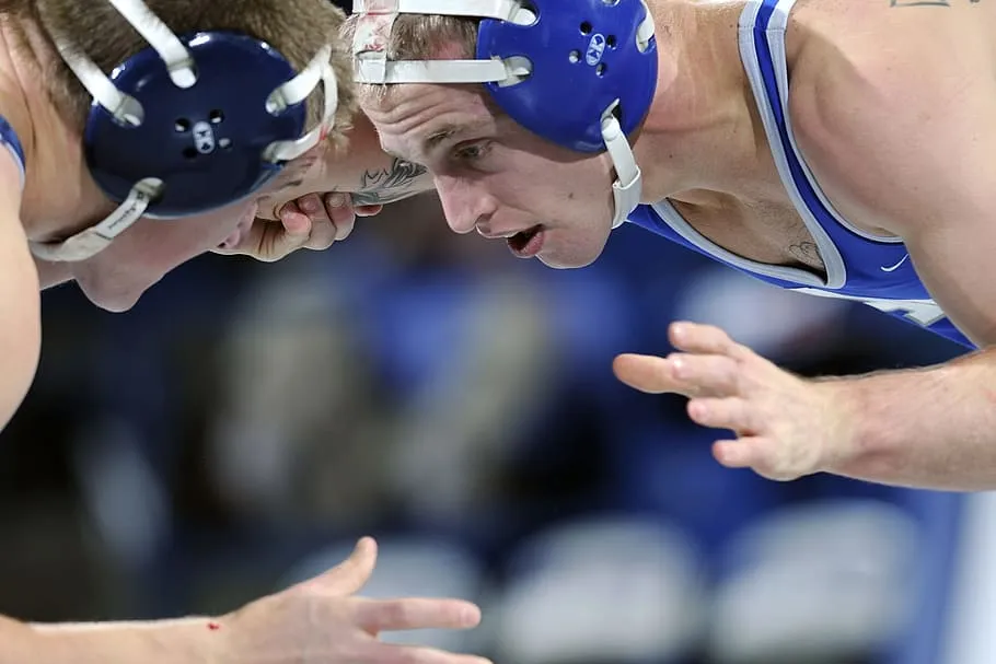 Two wrestlers in blue headgear locked head to head