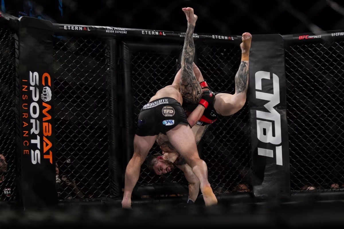 A takedown against the cage during a live combat sports event